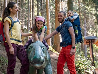 Familie an einer Saurier-Nachbildung auf dem Saurierpfad im UNESCO Global Geopark Thüringen Inselsberg – Drei Gleichen