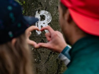 Zwei Menschen formen vor der Wegemarkierung des Rennsteigs ein Herz mit ihren Fingern