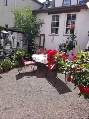 Terrasse mit Gartentisch und Stühlen im Hotel Phönix in Friedrichroda in der Inselbsergregion, Rosen blühen rot