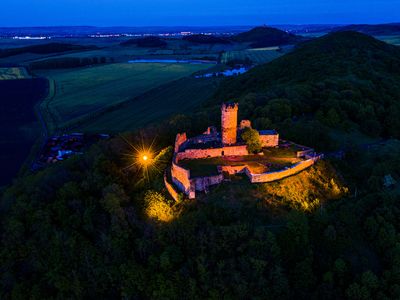 Drohnenaufnahme der beleuchteten Mühlburg im Thüringer Burgenland Drei Gleichen bei Nacht