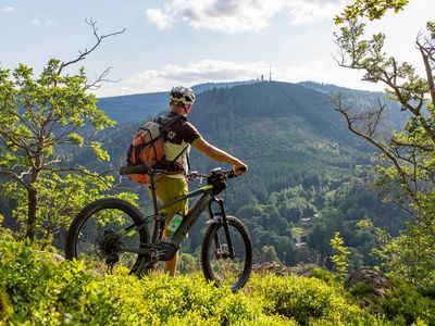 Mountainbiker in Bad Tabarz genießt eine Pause mit Blick auf den Inselsberg im UNESCO Global Geopark Thüringen Inselsberg – Drei Gleichen