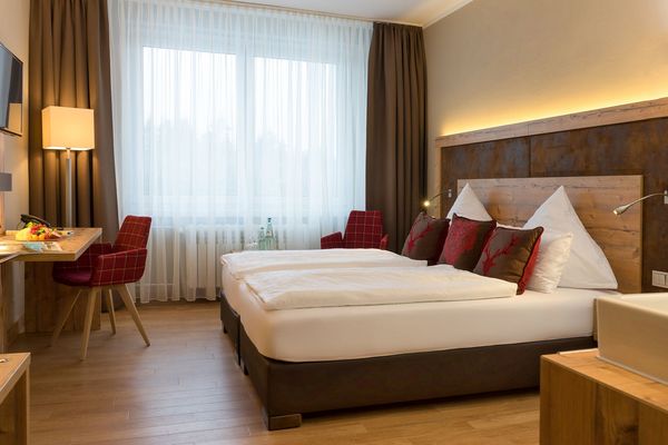 Doppelbett mit Schreibtisch, Stuhl und TV im Waldhotel Berghof Luisenthal in der Talsperrenregion im Thüringer Wald