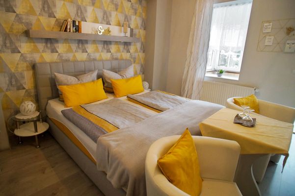 Ein Doppelbett mit Sitzgelegenheit im Hotel Villa Phönix in Friedrichroda (Inselsbergregion)