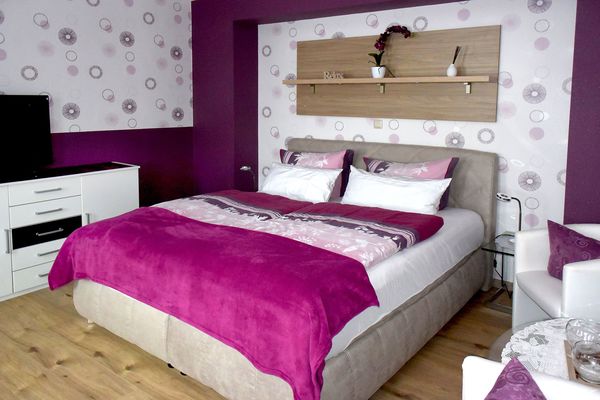 Ein Doppelbett mit Sitzgelegenheit und TV im Hotel Villa Phönix in Friedrichroda (Inselsbergregion)