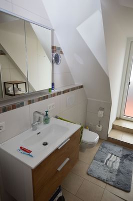 Helles Badezimmer mit Waschbecken, Spiegel und WC im Ferienhaus Urban