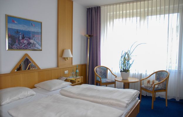 Doppelbett mit Tisch und zwei Stühlen im Waldhotel Berghof Luisenthal in der Talsperrenregion im Thüringer Wald