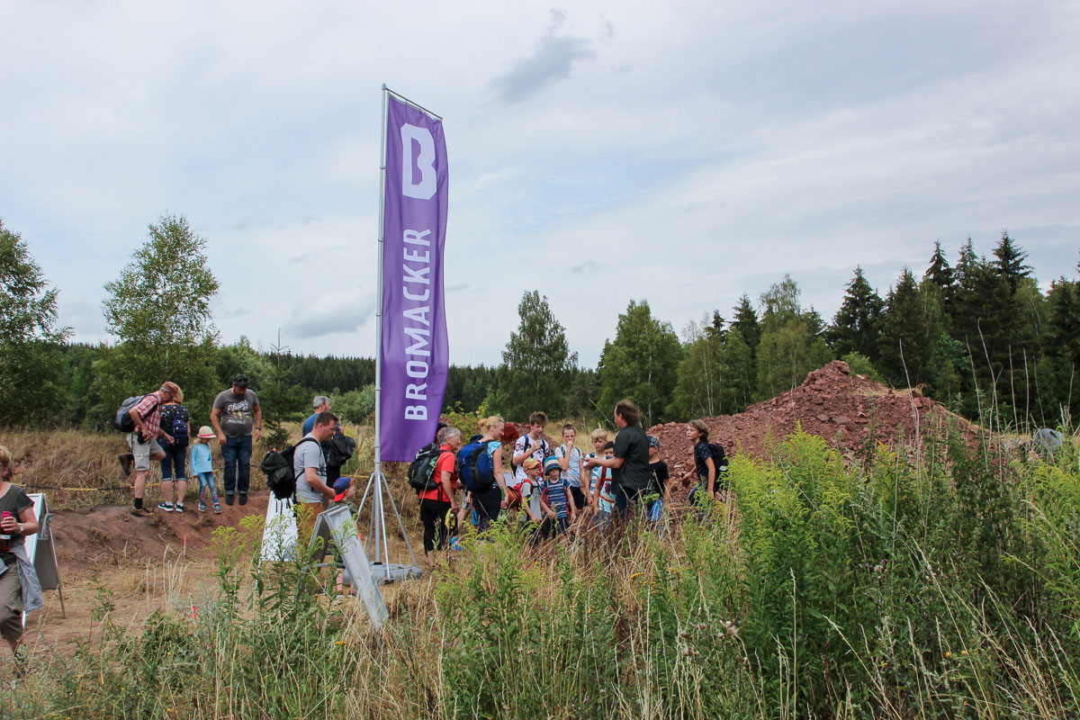 Kinder und Erwachsene befinden sich an der Ausgrabungsstätte Bromacker bei Tambach-Dietharz im UNESCO Global Geopark Thüringen Inselsberg – Drei Gleichen und hören einem Geologe zu